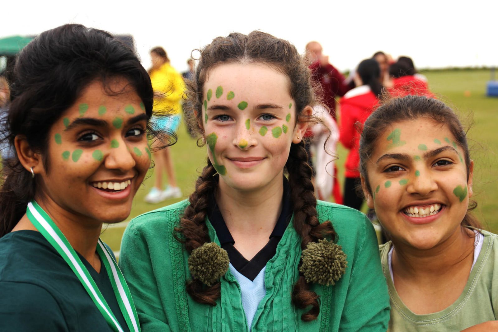 Retrato de tres chicas, con rostro pintado, con motivo a torneo de deportes - Roedean School