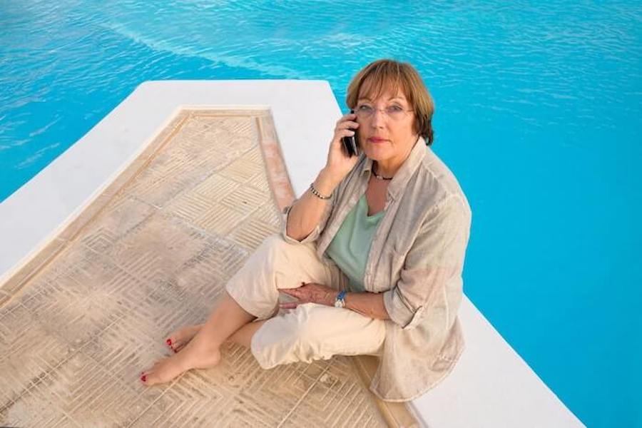 mujer hablando por teléfono al lado de una piscina